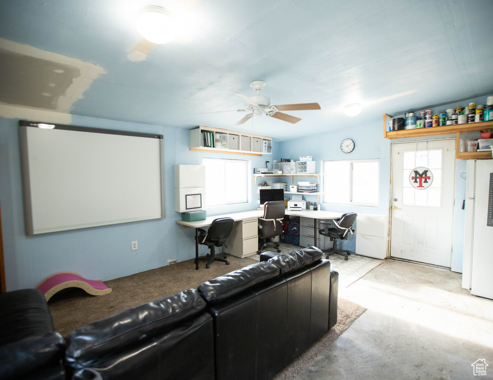 Living room featuring built in study area, concrete floors, and ceiling fan