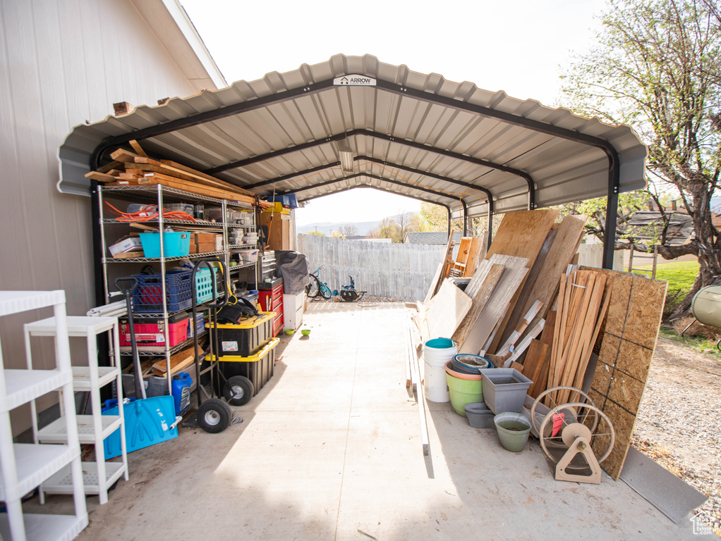 View of parking / parking lot with fence and a detached carport