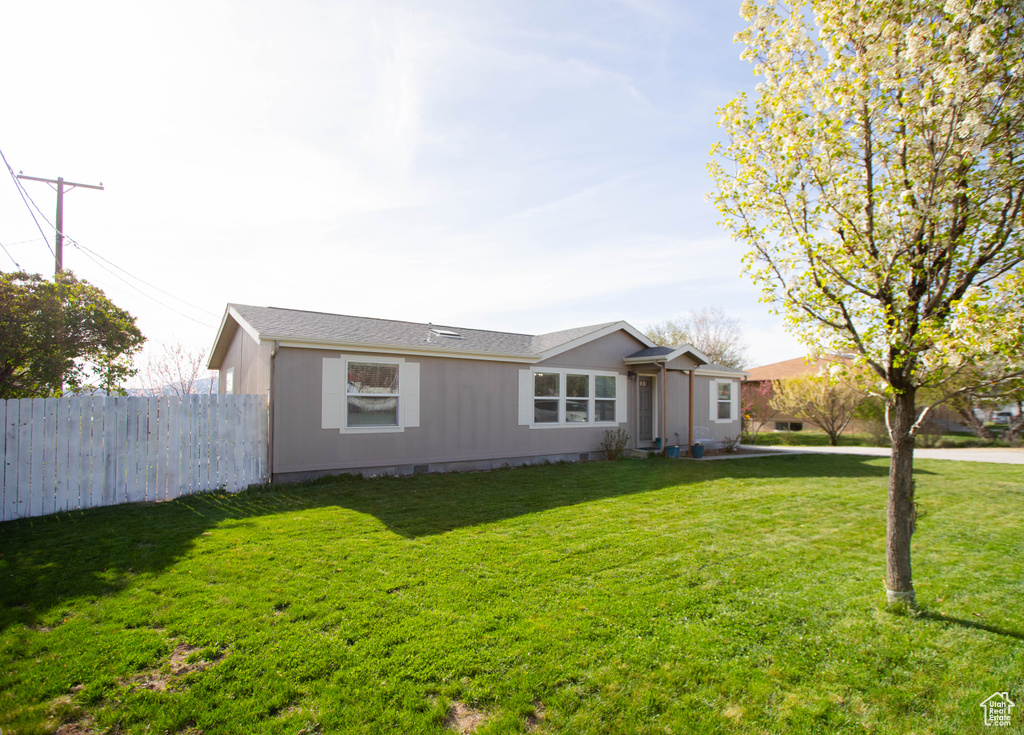 Ranch-style home featuring a front lawn and fence