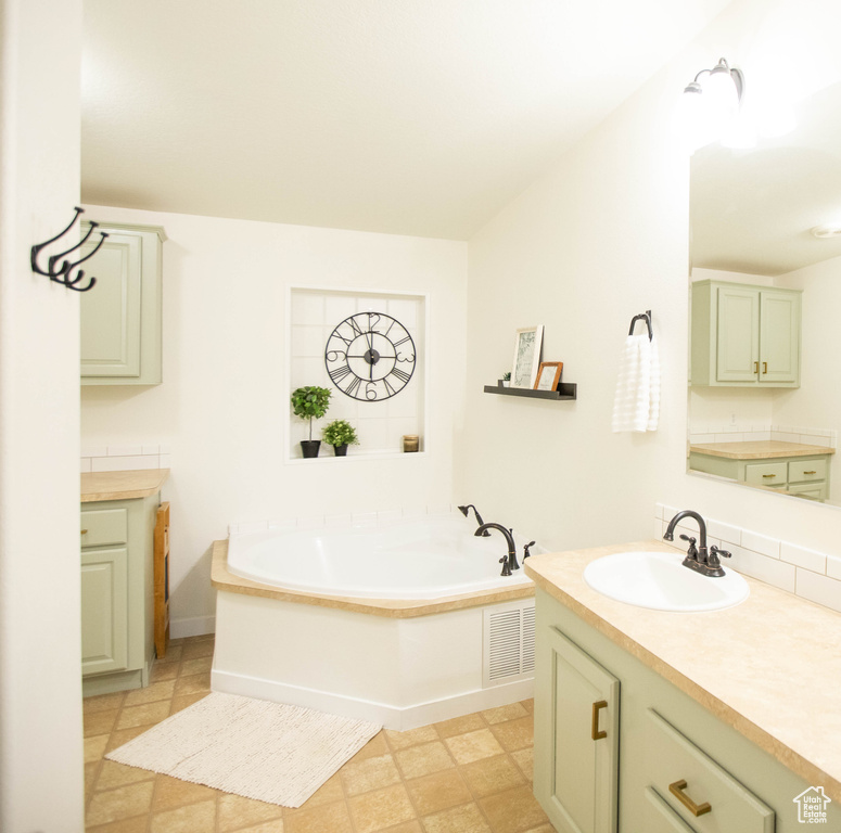 Bathroom with a bath, vanity, and visible vents