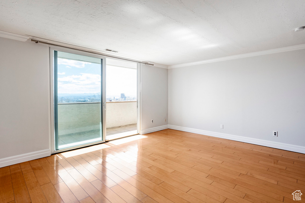 Unfurnished room with light wood-style floors and crown molding
