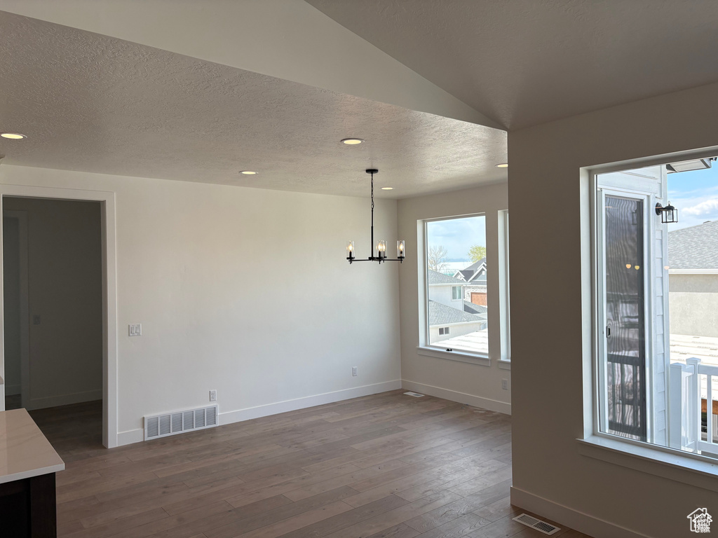 Unfurnished dining area with baseboards, visible vents, a chandelier, and dark wood-style flooring