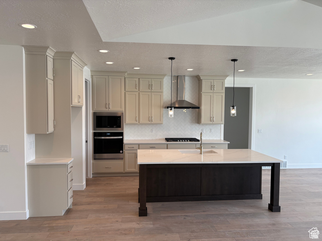 Kitchen featuring wall chimney exhaust hood, stainless steel appliances, light wood finished floors, a sink, and baseboards