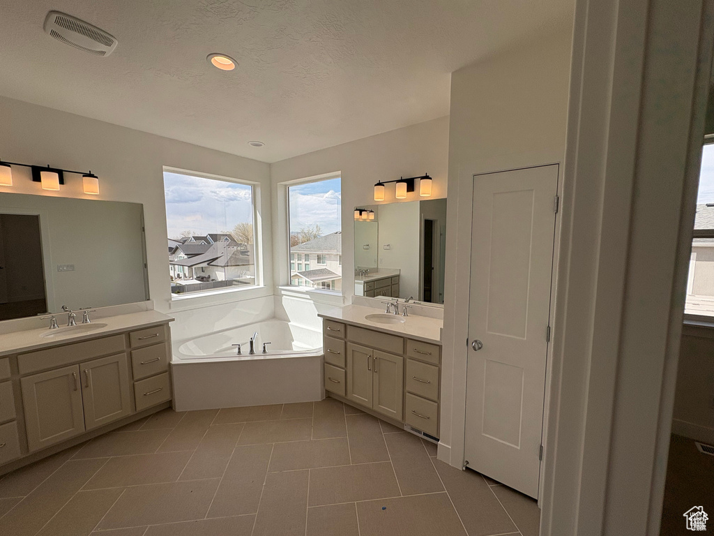 Full bath featuring two vanities, a bath, visible vents, and a sink
