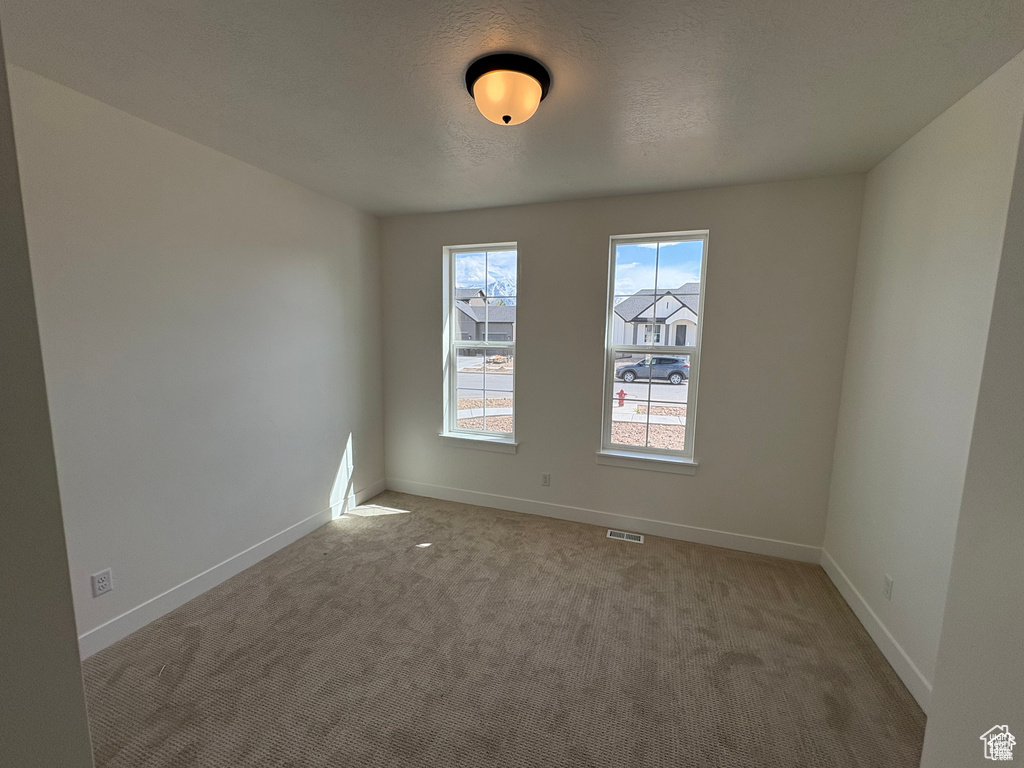 Carpeted spare room with baseboards and visible vents
