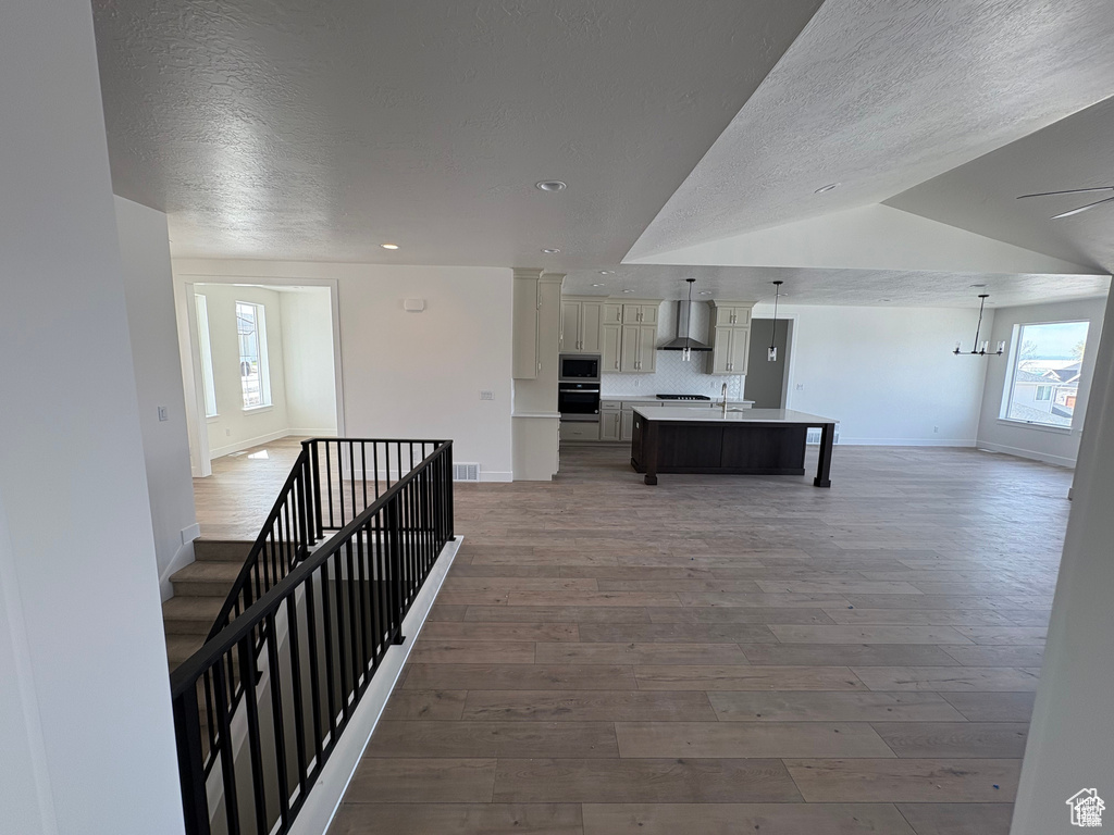 Hallway with hardwood / wood-style flooring, baseboards, a textured ceiling, and a wealth of natural light