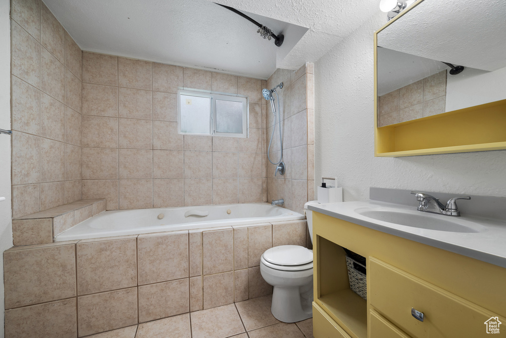 Bathroom featuring tiled shower / bath combo, tile patterned flooring, vanity, and toilet
