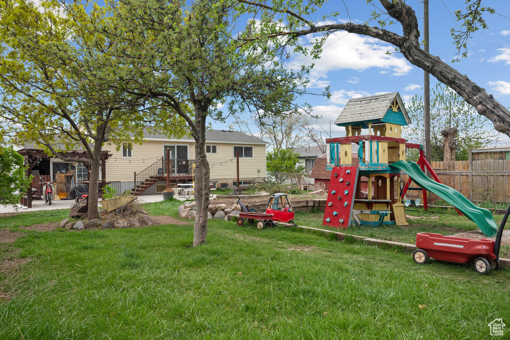 View of jungle gym with fence and a lawn