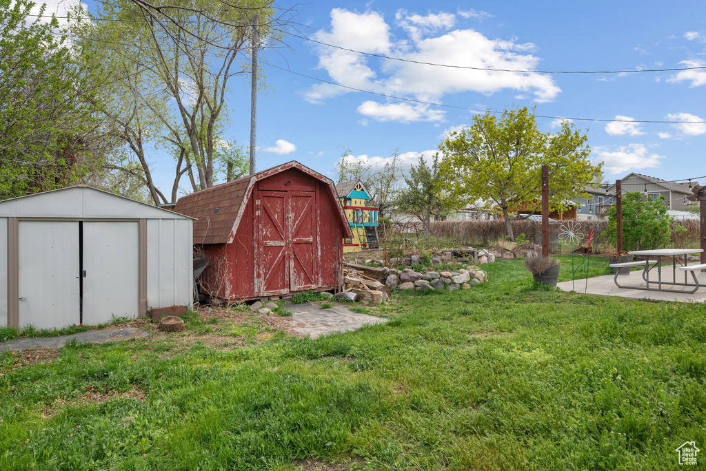View of yard featuring an outdoor structure, a storage unit, a patio area, and fence