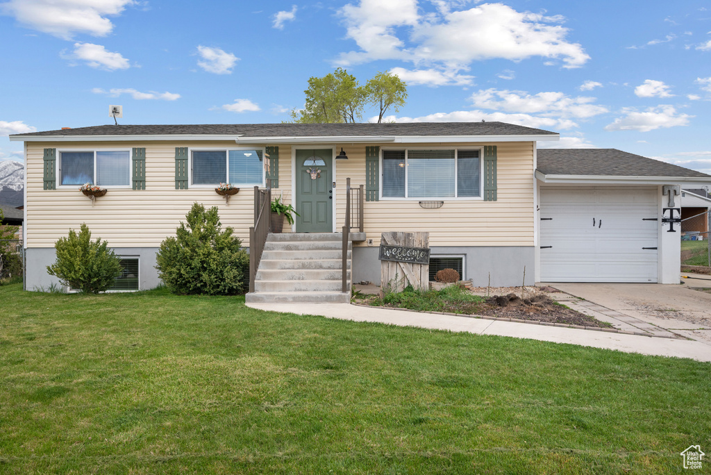 Ranch-style home featuring concrete driveway, a front lawn, and a garage