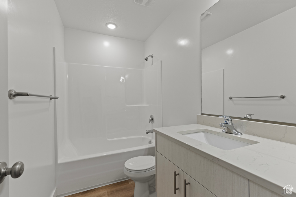 Bathroom with wood finished floors, visible vents, toilet, vanity, and shower / bathtub combination