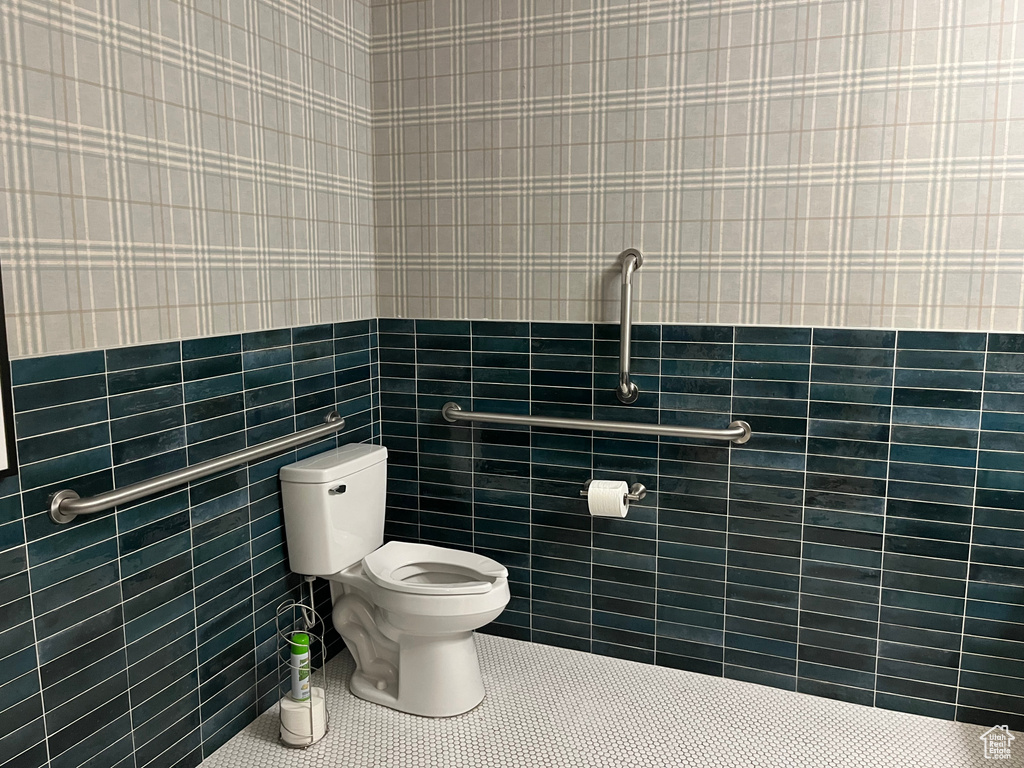 Bathroom featuring toilet, tile patterned floors, and tile walls