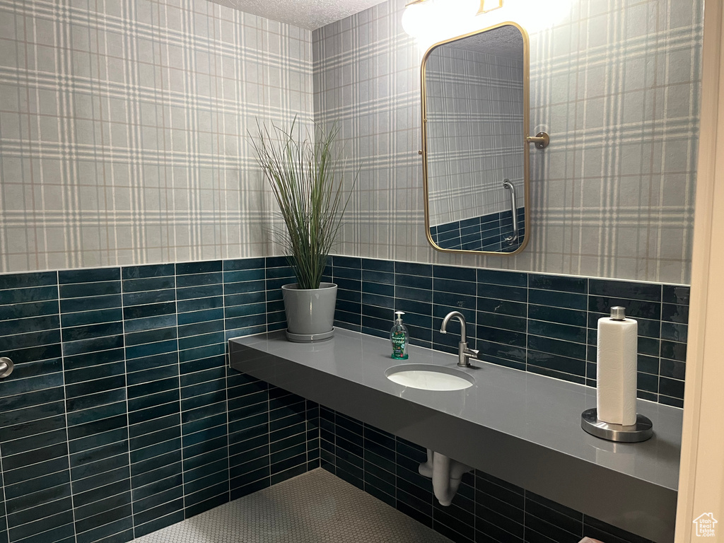 Bathroom featuring wallpapered walls and a sink