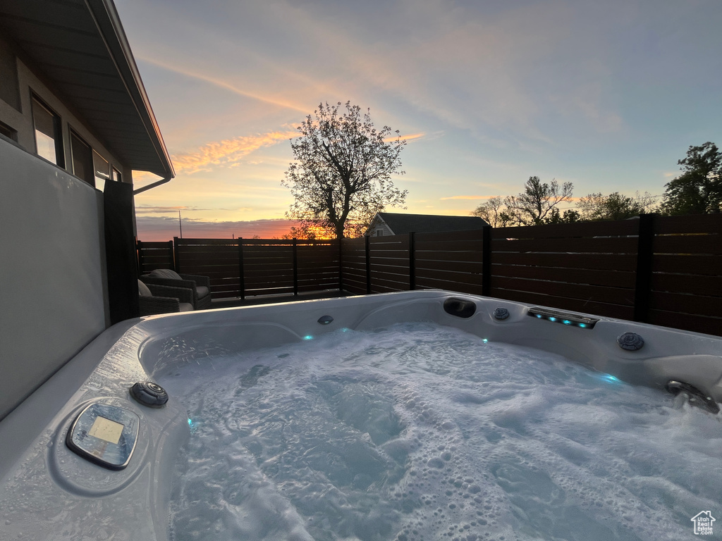 Patio terrace at dusk featuring a hot tub