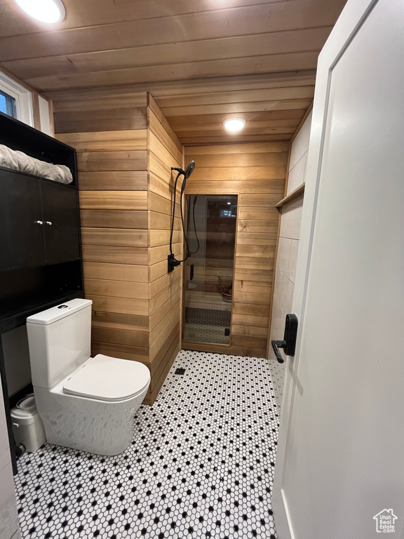 Bathroom with wood walls, toilet, a tile shower, wood ceiling, and tile patterned floors