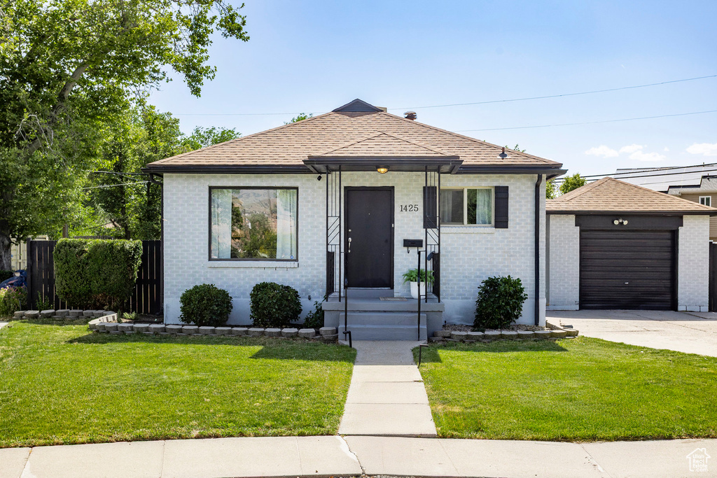 Bungalow featuring concrete driveway, an outdoor structure, and brick siding