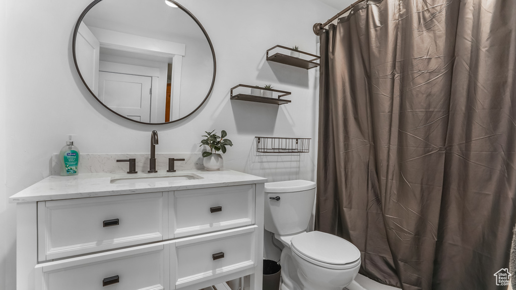 Full bathroom with toilet, vanity, and a shower with shower curtain