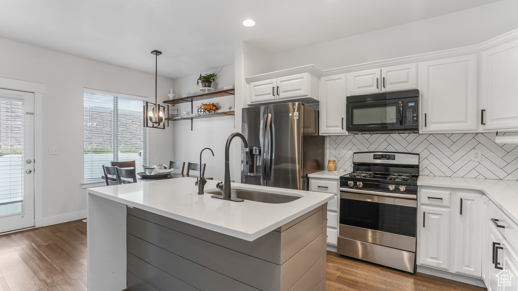 Kitchen with a sink, dark wood finished floors, white cabinetry, decorative backsplash, and appliances with stainless steel finishes