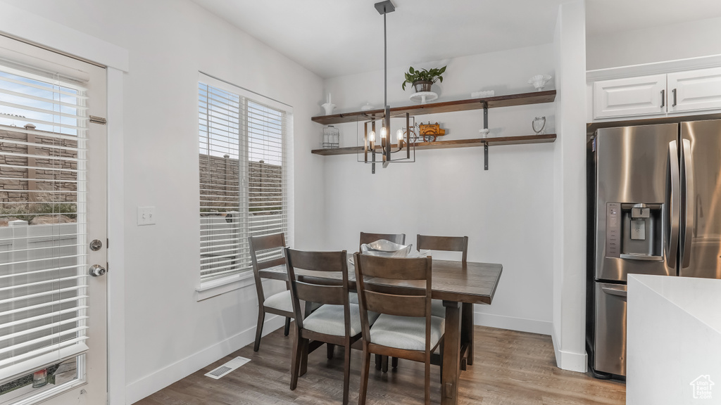 Dining room with visible vents, baseboards, wood finished floors, and an inviting chandelier