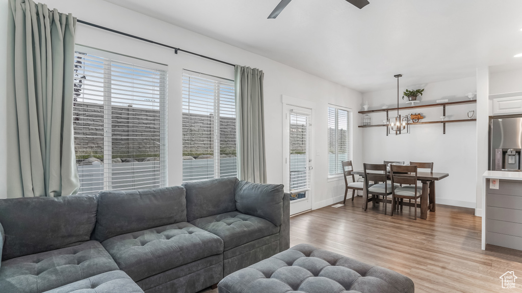 Living room featuring light wood-type flooring, baseboards, and ceiling fan with notable chandelier