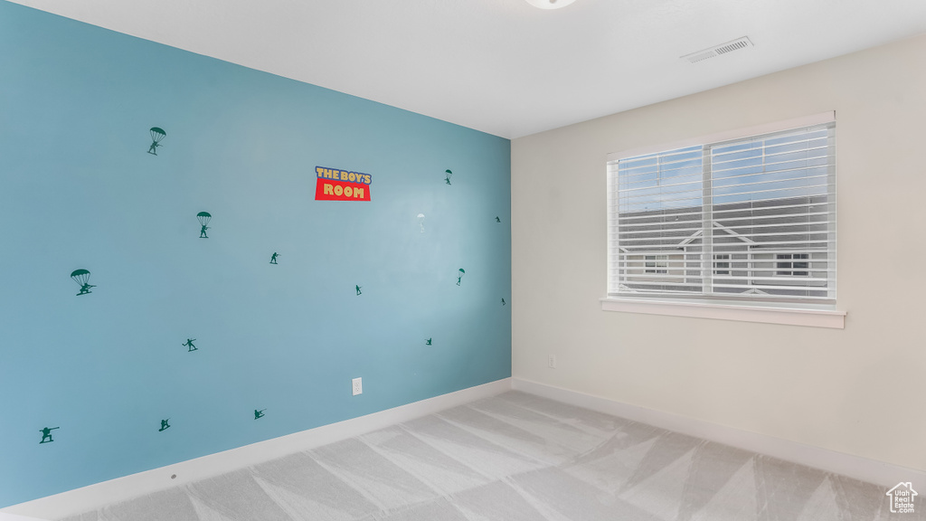 Spare room featuring visible vents, baseboards, and light carpet