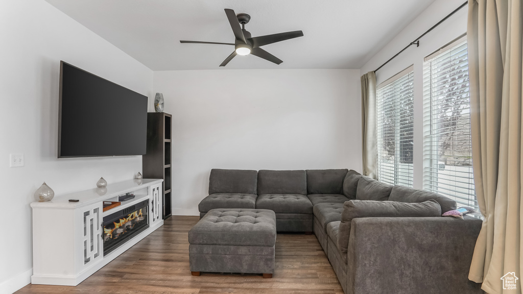 Living area featuring a glass covered fireplace, wood finished floors, and ceiling fan