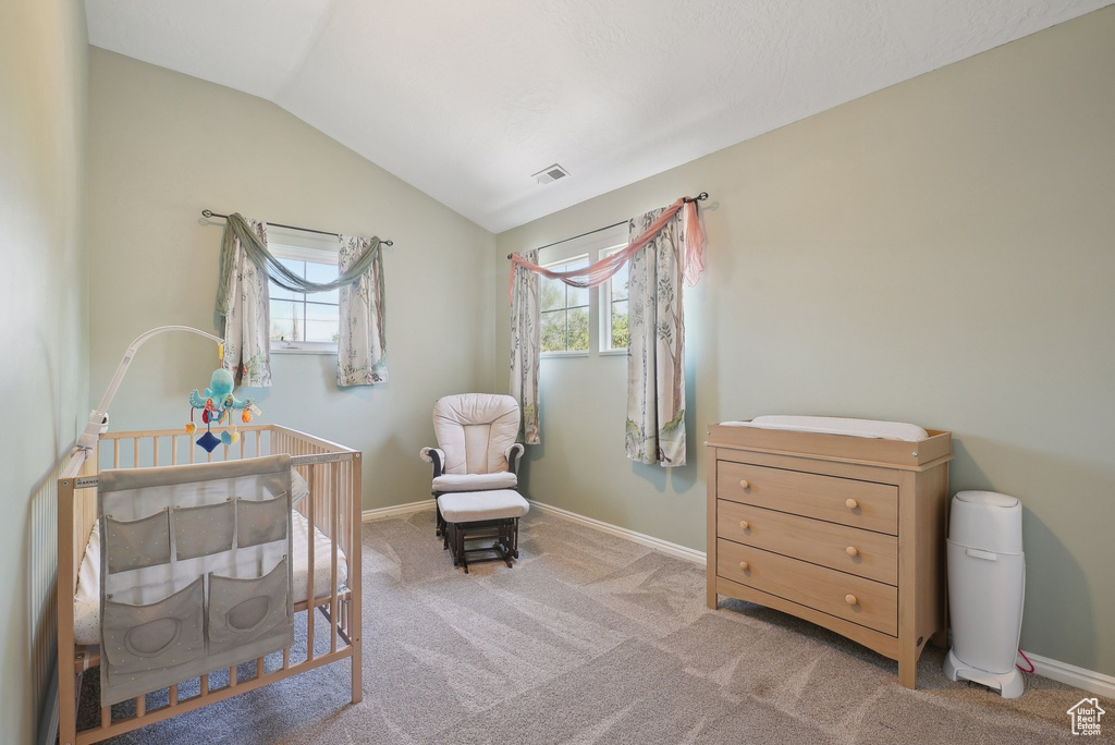 Bedroom featuring multiple windows, visible vents, a crib, and vaulted ceiling