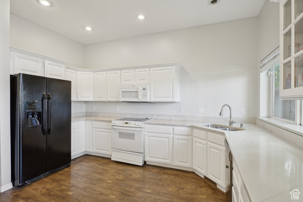 Kitchen featuring a sink, white appliances, white cabinetry, recessed lighting, and glass insert cabinets