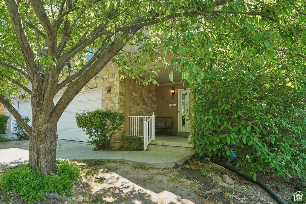 Entrance to property featuring a garage, covered porch, and stone siding
