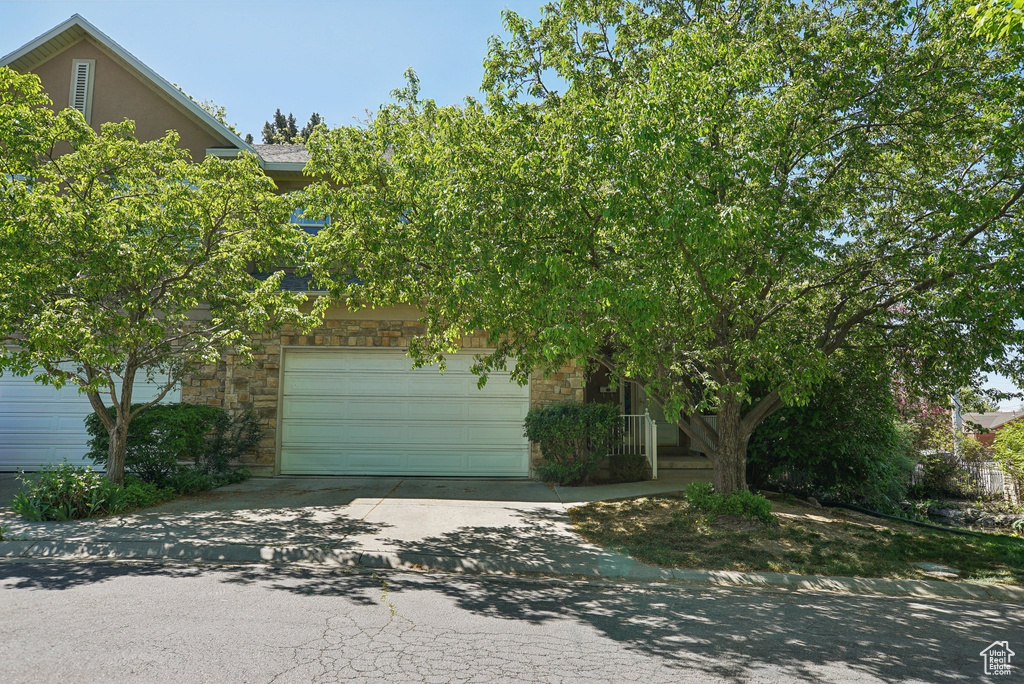 View of front of property with stucco siding, driveway, and stone siding