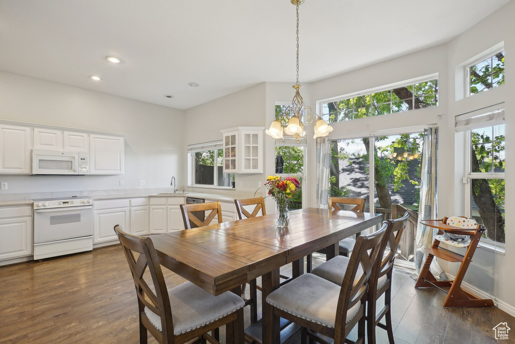 Dining area with recessed lighting, an inviting chandelier, plenty of natural light, and dark wood-type flooring