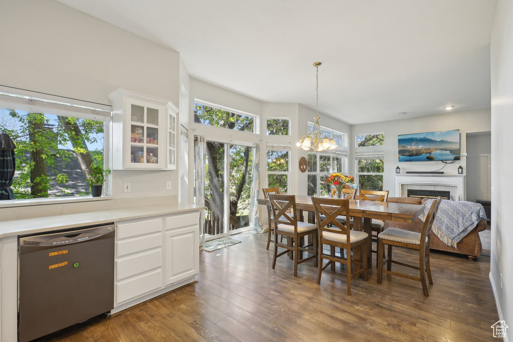 Dining area with a fireplace, a chandelier, and dark wood-type flooring