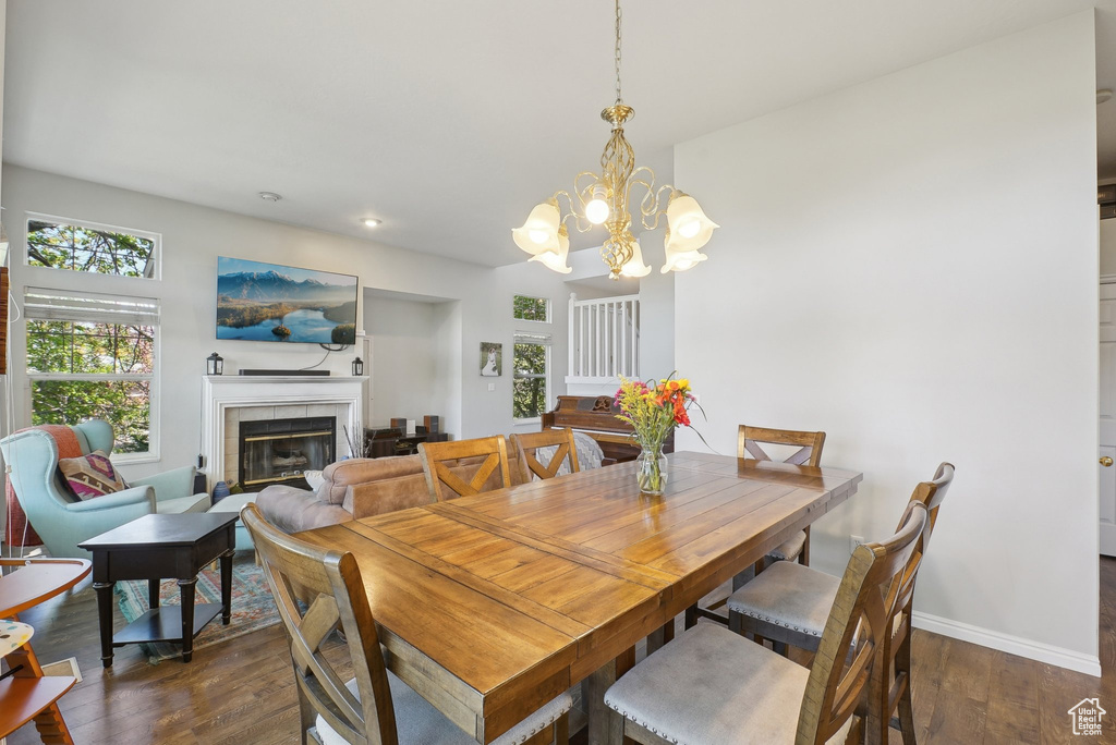 Dining room featuring baseboards, dark wood-type flooring, recessed lighting, a tile fireplace, and a notable chandelier