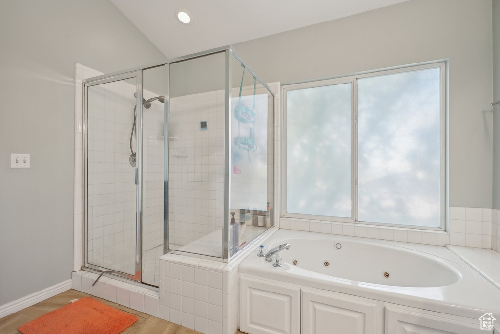 Full bathroom featuring plenty of natural light, a whirlpool tub, a stall shower, and wood finished floors