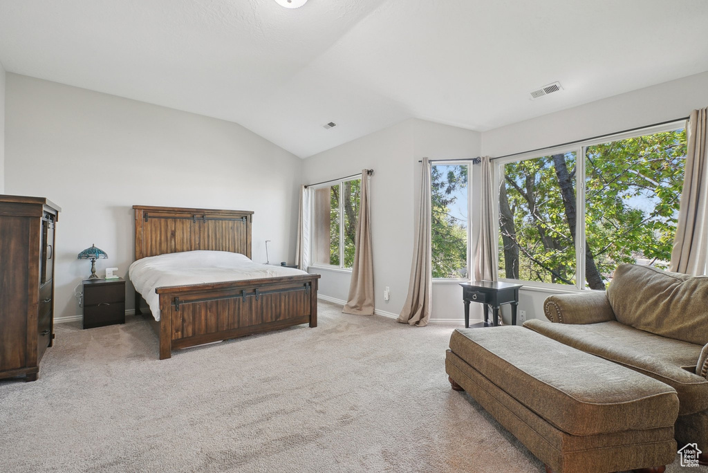 Bedroom featuring visible vents, baseboards, vaulted ceiling, and light carpet