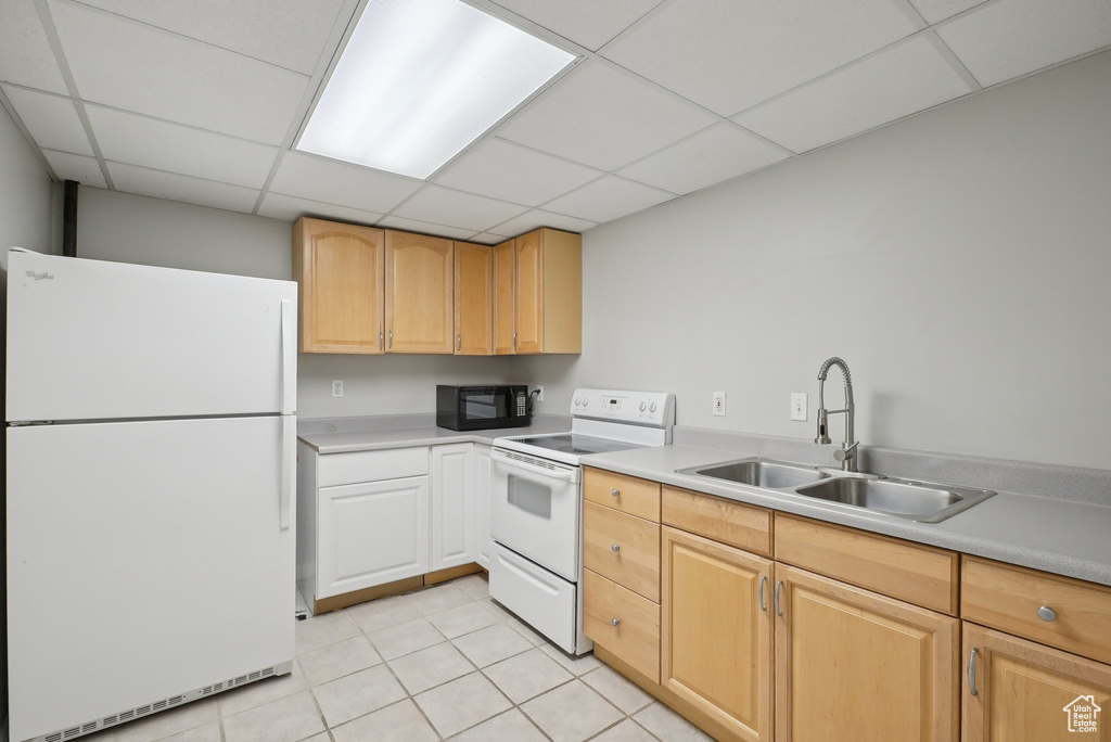 Kitchen with white appliances, light tile patterned floors, a paneled ceiling, and a sink