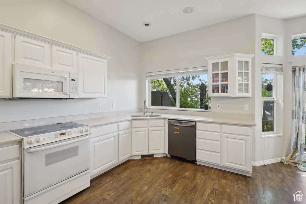 Kitchen featuring a sink, a wealth of natural light, white appliances, and glass insert cabinets