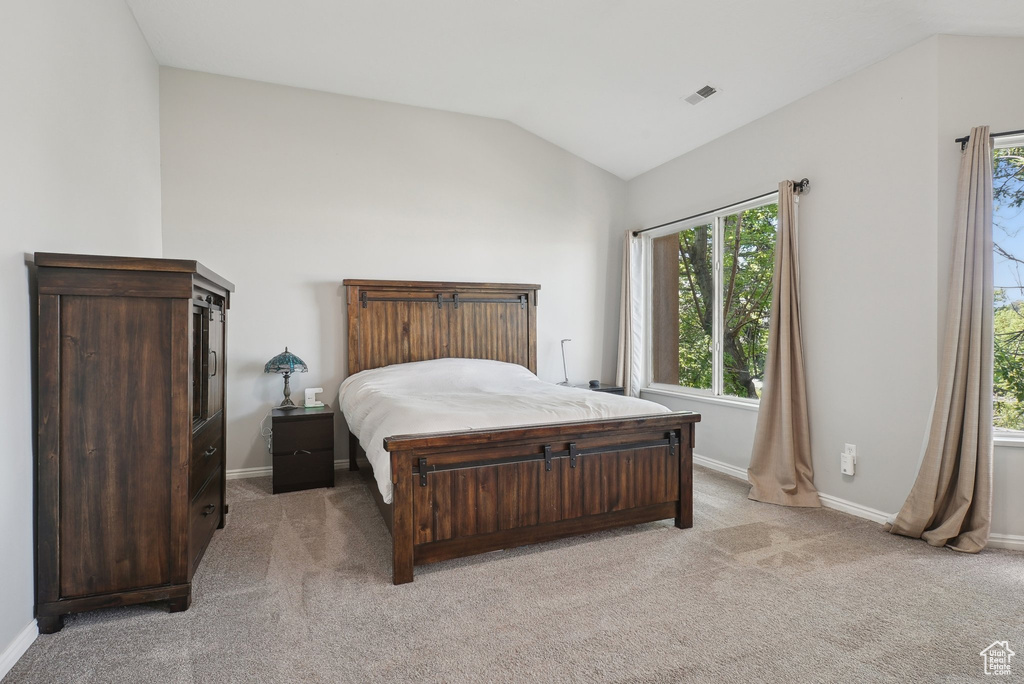 Bedroom featuring baseboards, vaulted ceiling, and light colored carpet