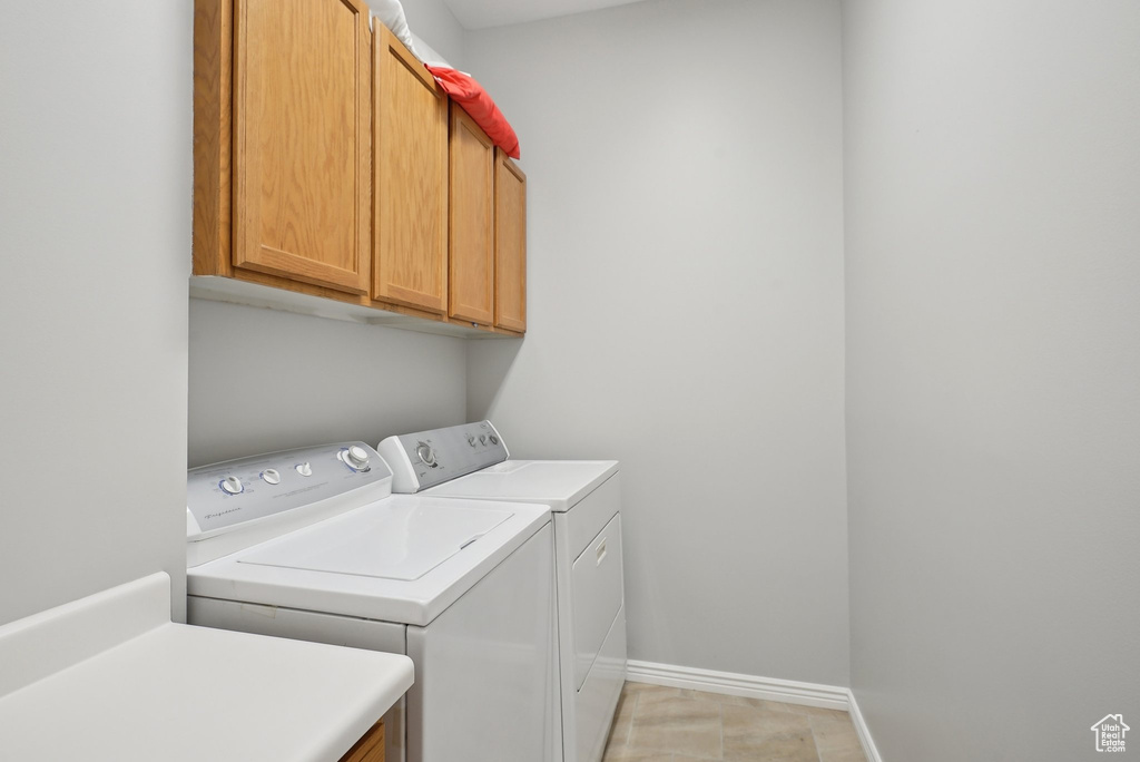 Laundry area with cabinet space, separate washer and dryer, and baseboards