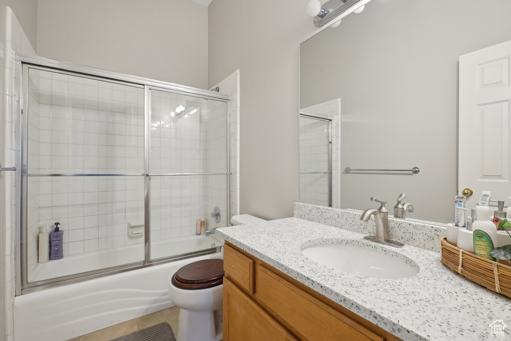 Full bathroom with vanity, bath / shower combo with glass door, and toilet