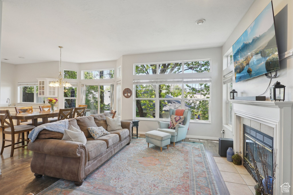Living room featuring a tiled fireplace, wood finished floors, and a chandelier