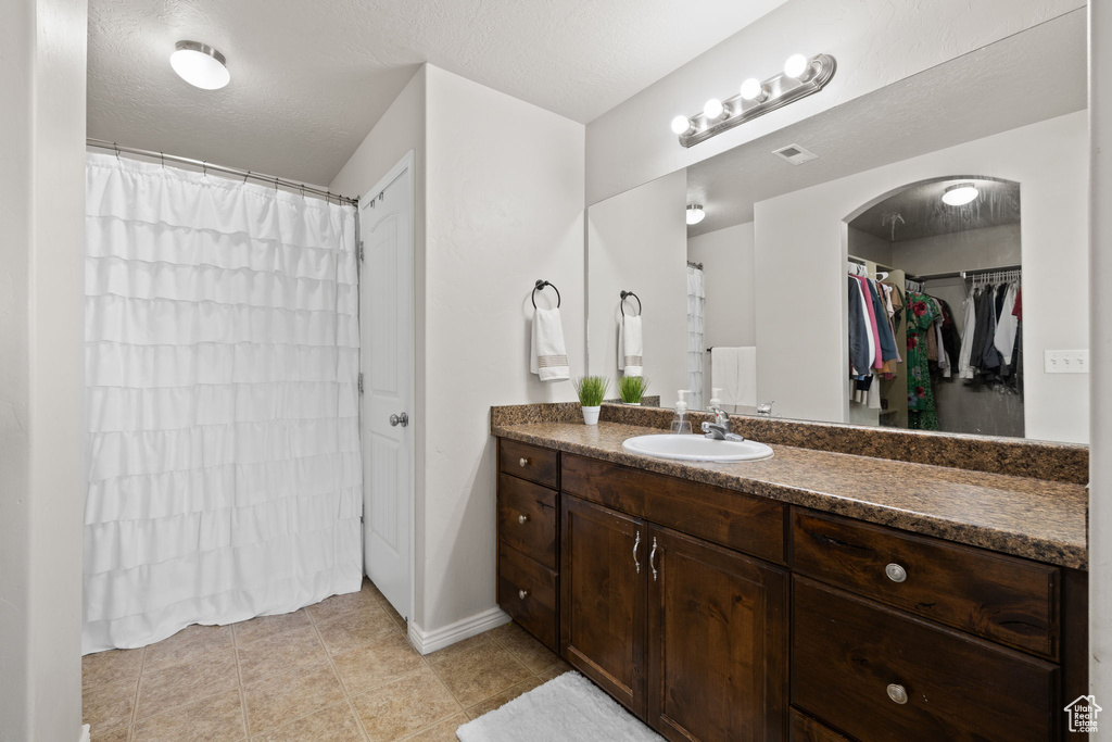 Full bathroom featuring baseboards, visible vents, tile patterned floors, and vanity