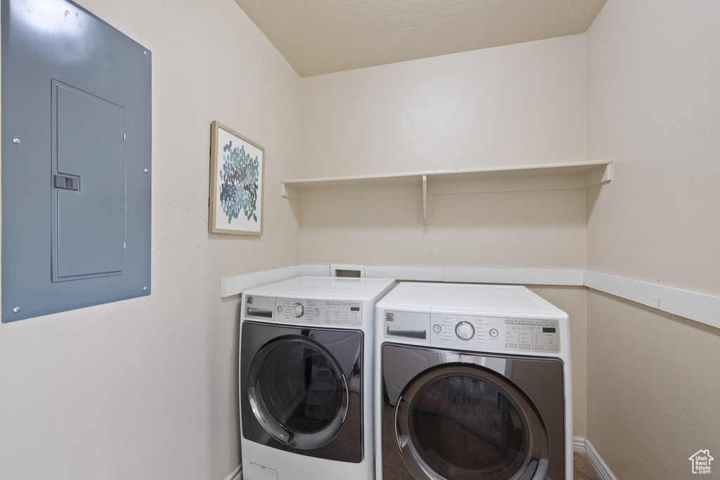 Clothes washing area with electric panel, baseboards, washer and clothes dryer, and laundry area