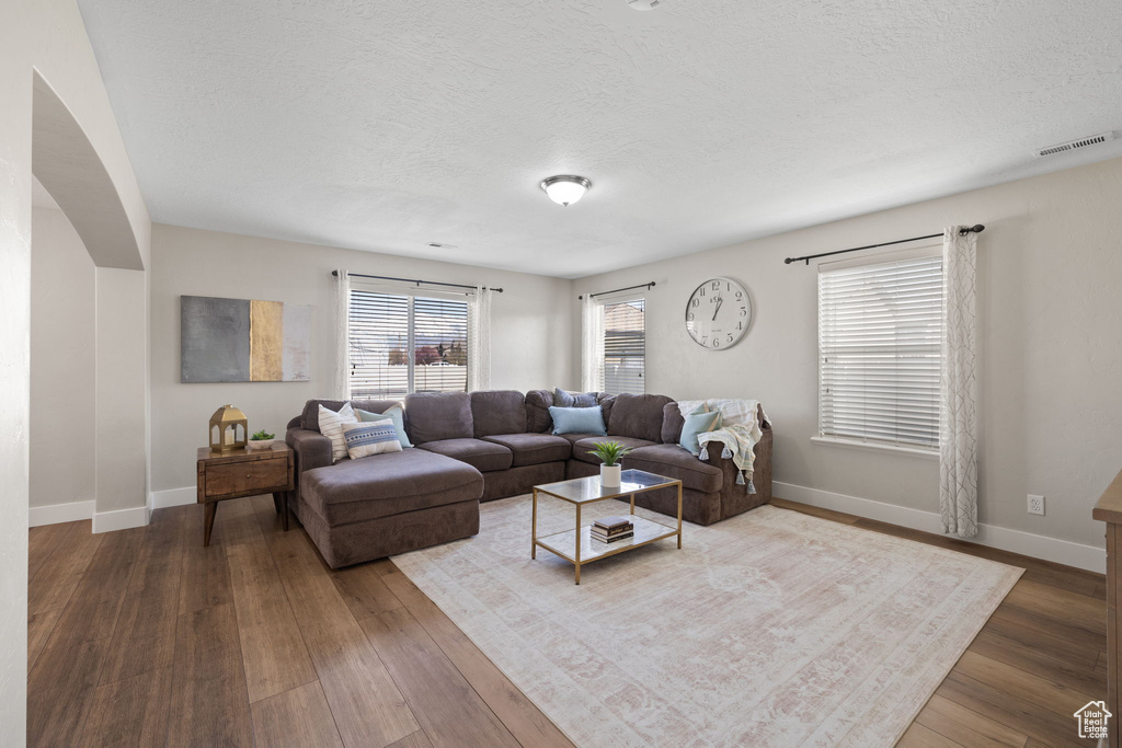 Living area featuring hardwood / wood-style flooring, baseboards, a textured ceiling, and visible vents