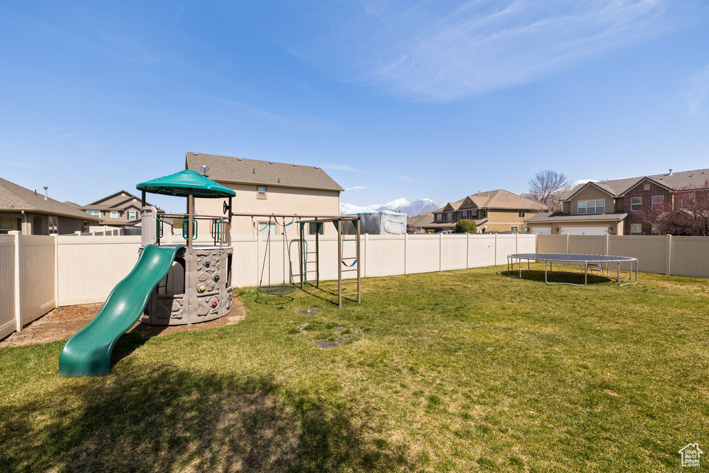 View of yard featuring a residential view, a trampoline, a fenced backyard, and a playground