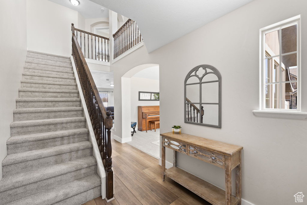 Stairs featuring baseboards, wood finished floors, and arched walkways