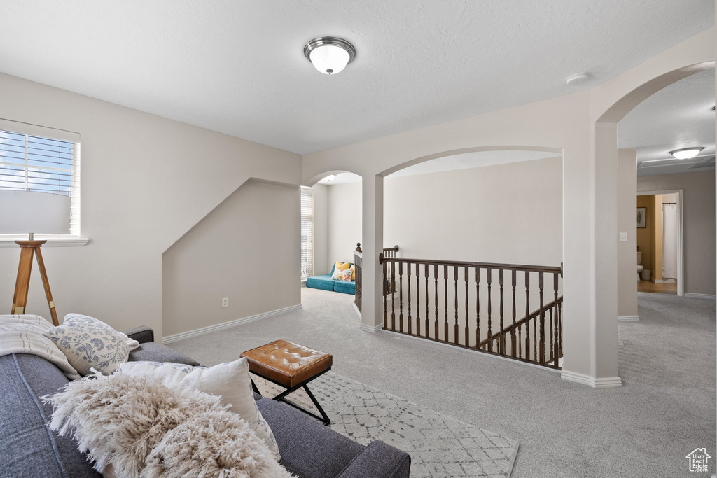 Carpeted living room with arched walkways and baseboards