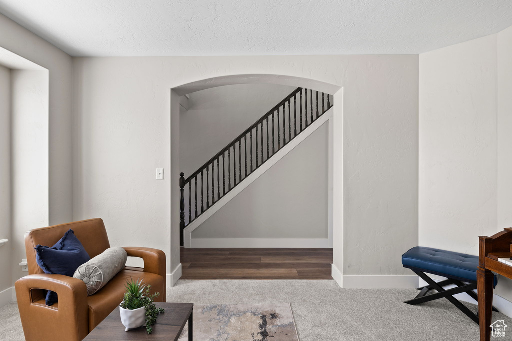 Interior space with arched walkways, baseboards, carpet floors, and stairway