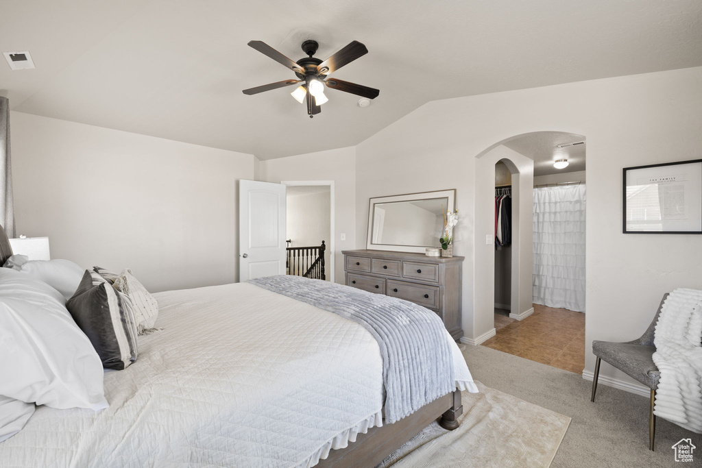 Bedroom with vaulted ceiling, a spacious closet, arched walkways, light carpet, and visible vents