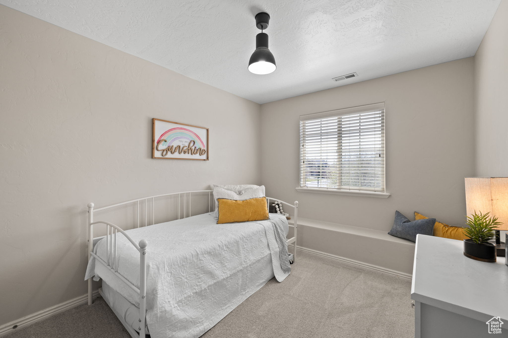 Bedroom featuring a textured ceiling, carpet, visible vents, and baseboards